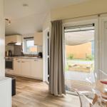 Küche, Essbereich und Terrasse mit Gartenmöbeln und Sonnensegel.