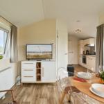 Wohn- und Essbereich mit TV, Esstisch und Blick auf die Küche.