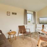 Wohn- und Essbereich mit Sofa, Stuhl, TV und Tisch.