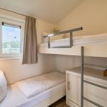 Zimmer mit Doppelstockbett, Fenster und Spielzeugkorb.