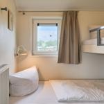 Zimmer mit Doppelstockbett, Fenster und Heizung.