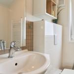 Bad mit Waschbecken, Spiegel, Toilette und Fenster