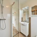 Badezimmer mit Dusche, Waschbecken und Spiegelschrank.