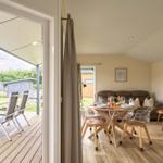 Ein Essbereich mit Tisch und Stühlen. Durch eine Tür ist eine Terrasse mit Stühlen sichtbar.