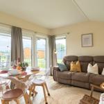 Wohn- und Essbereich mit Sofa, Tisch und Sicht auf den Garten.