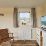 Ein Raum mit einem Fenster, einem Fernseher und einem Stuhl.