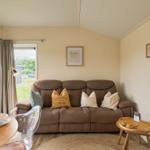 Ein Wohnzimmer mit braunem Sofa, Tisch und Fenster zur Außenseite.