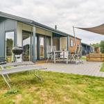 Modernes Ferienhaus mit Terrasse, Grill und Sitzgelegenheiten im Freien.