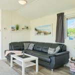 Wohnzimmer mit Sofa, Couchtisch und Fenster. Schlafzimmer im Hintergrund sichtbar.