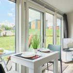 Esstisch mit Platz für zwei, großes Fenster mit Blick auf Grünfläche.