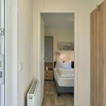 Schlafzimmer mit Bett, Nachttisch und Kleiderschrank. Durchgang zur Terrasse mit Gartenblick.