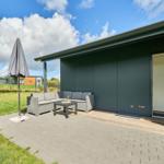 Terrasse mit Sitzgruppe, Sonnenschutz und Zugang zur Unterkunft.