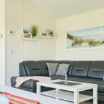 Ein Wohnzimmer mit einem schwarzen Sofa, einem weißen Tisch und Wandbildern.