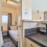 Schlafzimmer mit Bett und Fenster. Küchenzeile mit Wasserkocher.