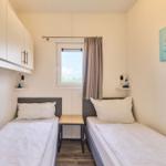 Zwei Einzelbetten mit Nachttisch und Fenster. Wandbild mit Delfinen.