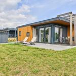 Moderne Ferienhaus mit Terrasse, Sonnenliegen und Holzüberdachung.
