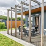 Terrasse mit Tisch, Stühlen und Hochstuhl unter Holzüberdachung.