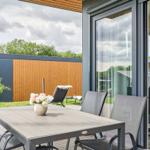 Terrasse mit Tisch und Stühlen, Blick auf Garten und Haus.