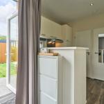 Küche mit Blick auf den Garten. Weiße Schränke und Holzboden.