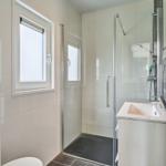 Badezimmer mit Dusche, Waschbecken und Fenster.