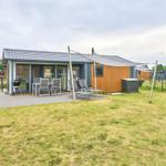 Modernes Ferienhaus mit Terrasse, Grill und Liegestühlen im Garten.