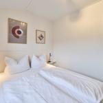 Schlafzimmer mit Doppelbett, zwei Nachttischen und Wandbildern.