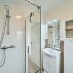 Bad mit Dusche, Waschbecken und Spiegel.