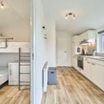 Schlafbereich mit Doppelstockbetten und Küchenbereich mit Arbeitsplatte und Fenster.