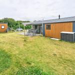 Modernes Ferienhaus mit Garten, Sitzgelegenheiten und Terrasse unter Sonnensegel.