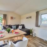 Essbereich mit Tisch, Stühlen und Sofa. Fenster und Vorhänge sichtbar.