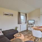 Wohn- und Essbereich mit Sofa, TV und Esstisch mit Stühlen.