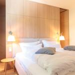 Schlafzimmer mit Doppelbett, Holzwand und Nachttisch