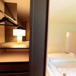 Schlafzimmer mit Bett, Kleiderschrank und Nachttischlampe.