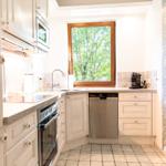 Küche mit Fenster, Spüle, Dunstabzug, Kaffeemaschine und Waschmaschine.