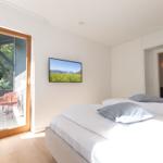 Schlafzimmer mit Bett, TV und Balkonzugang.