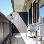 Terrasse mit zwei Stühlen und Tisch, Blick auf Gebäude und Berge.