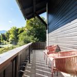 Terrasse mit zwei Stühlen und Tisch, Blick auf grüne Bäume und Gebäude.