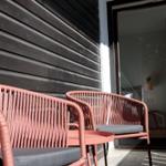 Terrasse mit zwei Stühlen und Tisch. Durch Glastür ist Schlafzimmer sichtbar.