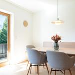 Esstisch mit Stühlen und Blick auf Balkon mit Bergblick.