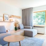 Wohnzimmer mit Sofa, Tisch und Blick auf grüne Bäume.