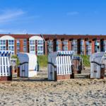 Strand mit Liegestühlen und Ferienhaus im Hintergrund.