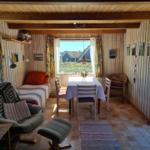 Living space with dining table, bed, and seating. Wooden walls and large windows.