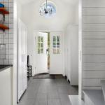 Küche mit Arbeitsplatte und Schränken, Flur mit Tür und Treppenhaus.