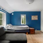 Schlafzimmer mit blauen Wänden, Bett, Sofa und Schreibtischstuhl.