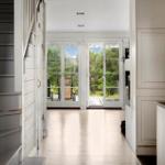 Helle Eingangshalle mit Blick auf Terrasse und Wald.