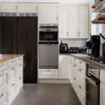 Küche mit weißen Schränken, schwarzer Kühlschrank und moderner Küchenzeile.