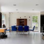 Esszimmer mit blauen Stühlen, Holzschrank und Fenstern zum Garten.