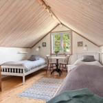 Zimmer mit zwei Betten, Holzdach und Fenster mit Blick.