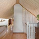 Schlafzimmer mit Holzdecke, Bett, Schrank und Blumen in Metalltopf.