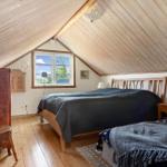 Schlafzimmer mit zwei Betten, Holzdecke und Fenster mit Blick nach draußen.